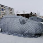 Zaawansowane systemy zarządzania temperaturą baterii: pompy ciepła, pre‑conditioning i wpływ na zasięg zimą Samochody pod pikowanymi pokrowcami na śniegu zimą w mieście