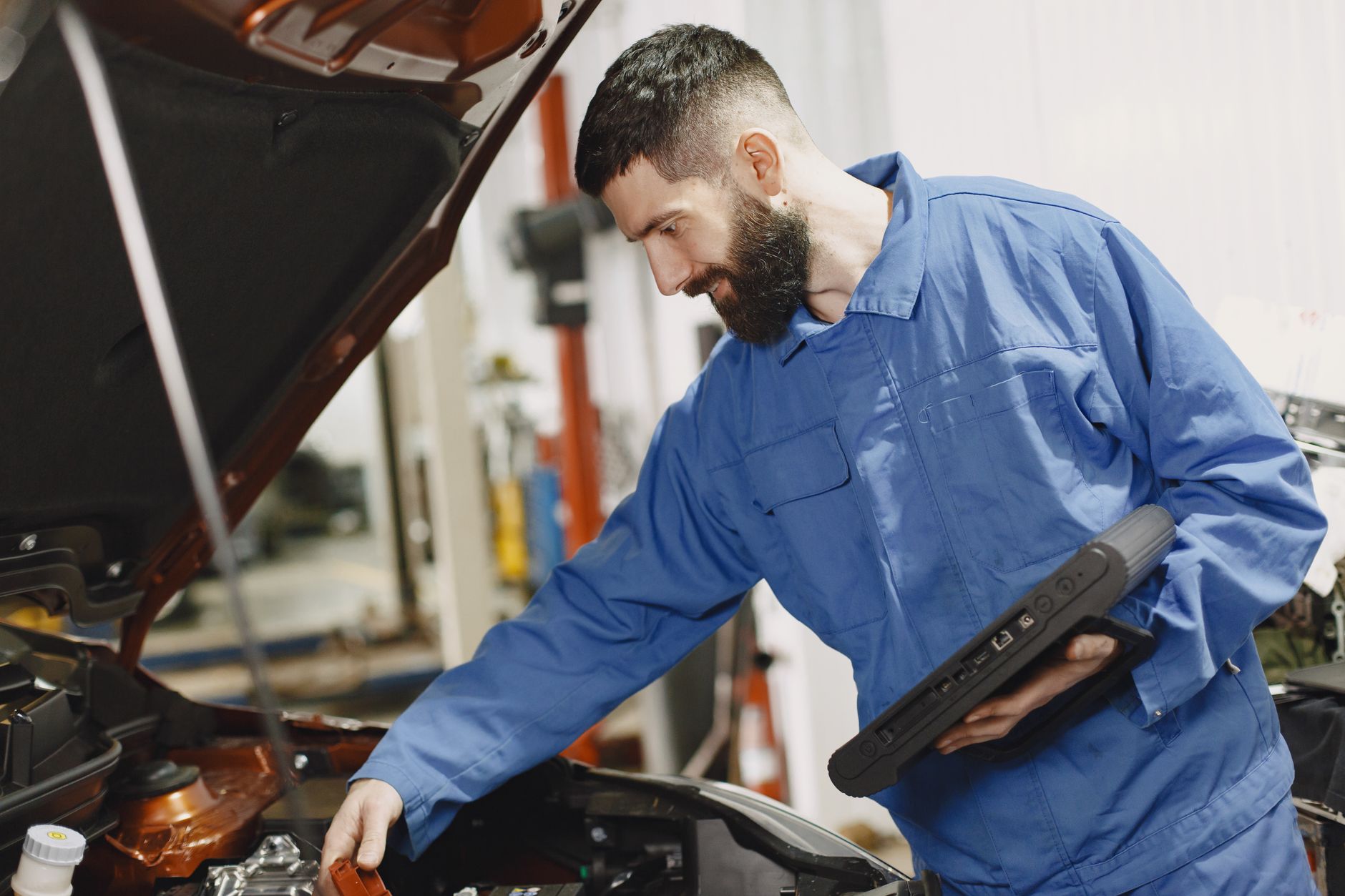 Mechanik w niebieskim kombinezonie sprawdza silnik Volkswagena w garażu